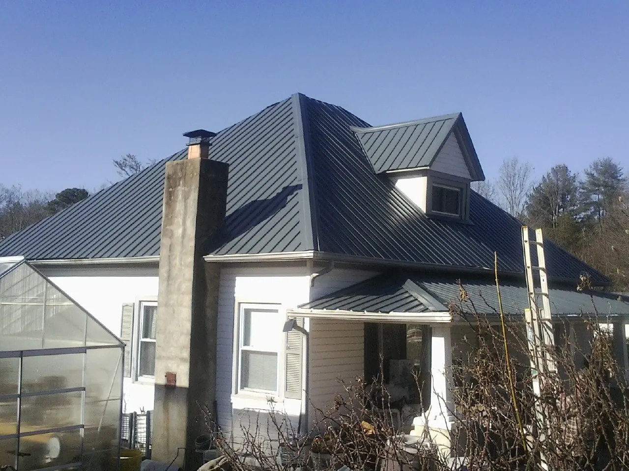 Dark blue standing seam metal roof on a white farmhouse with dormer — Slate & Tile Roof Repair by Roofing Brothers in Orbisonia