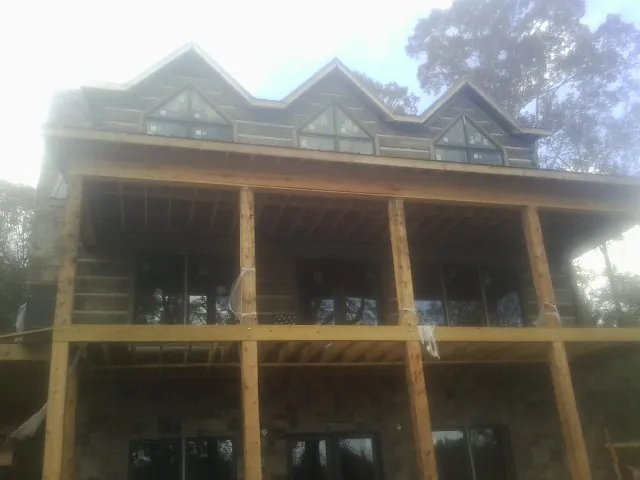 Dormers and porch framing on a large log home under construction — Roof Coating work by our crew in Orbisonia