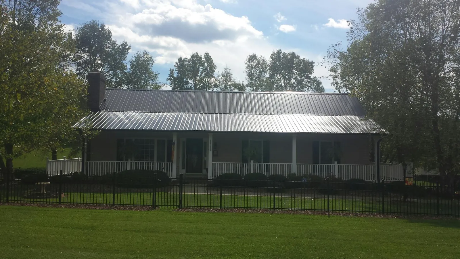Gray metal roof on a brick ranch with a full width front porch — Gutter Guard Installation work by our crew in Orbisonia